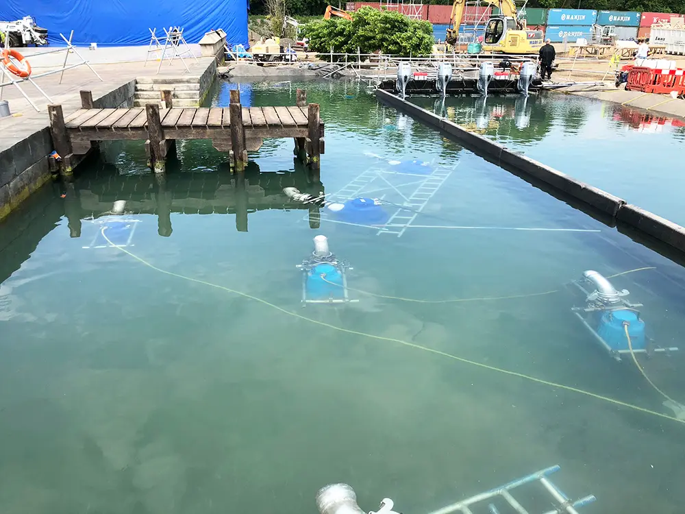 Multiple submersible pumps arranged in a studio tank to maintain consistent water movement on a film set.