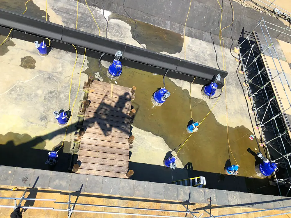 Submersible pumps laid out in a tank before water fill, ready for circulation on set.