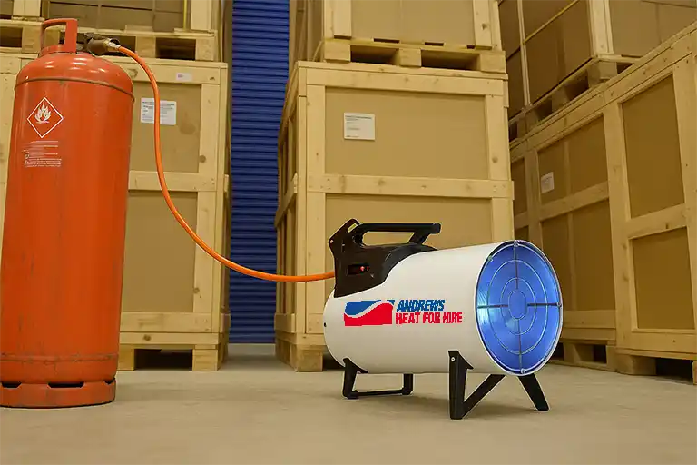 Industrial gas heater providing temporary warehouse heating, supporting the comparison of portable vs fixed heaters for large spaces.
