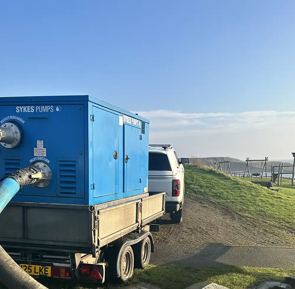 The delivery of a pumping unit, featuring a close-up of a Sykes pump trailer with a large suction hose attached