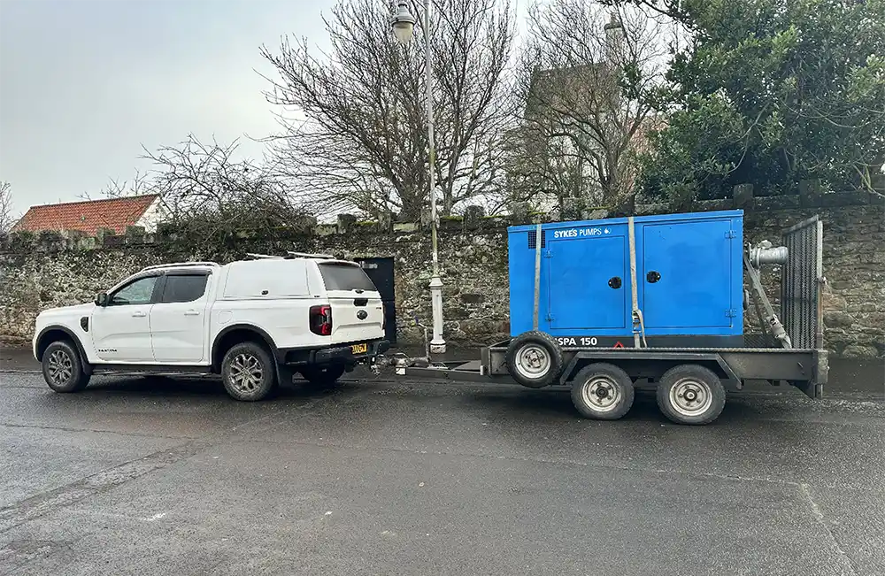 A white pickup truck transporting a Super Wispaset 150 pump
