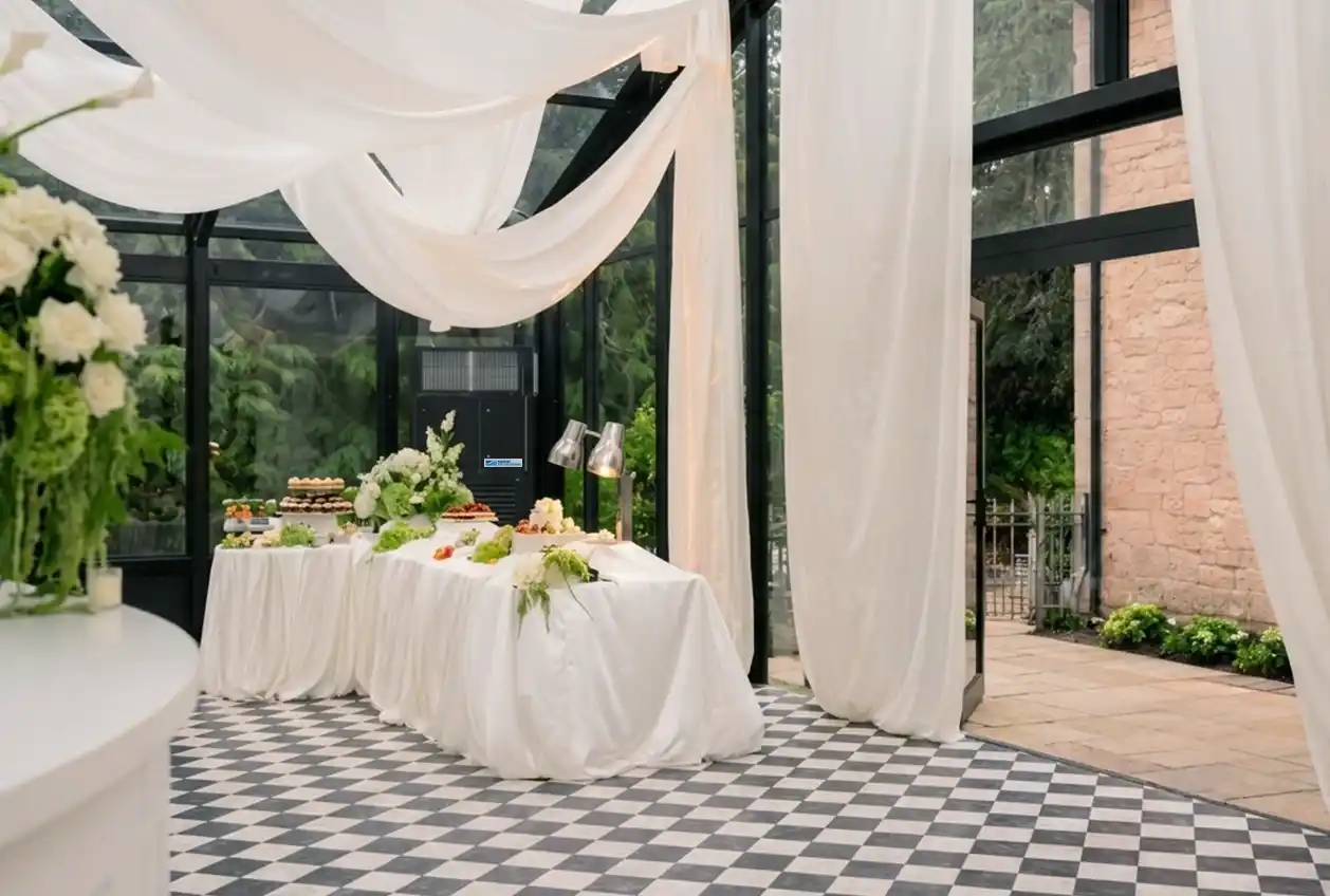 Black and white styled wedding reception inside a glass marquee, with the air handling unit blending into the venue's black window frames