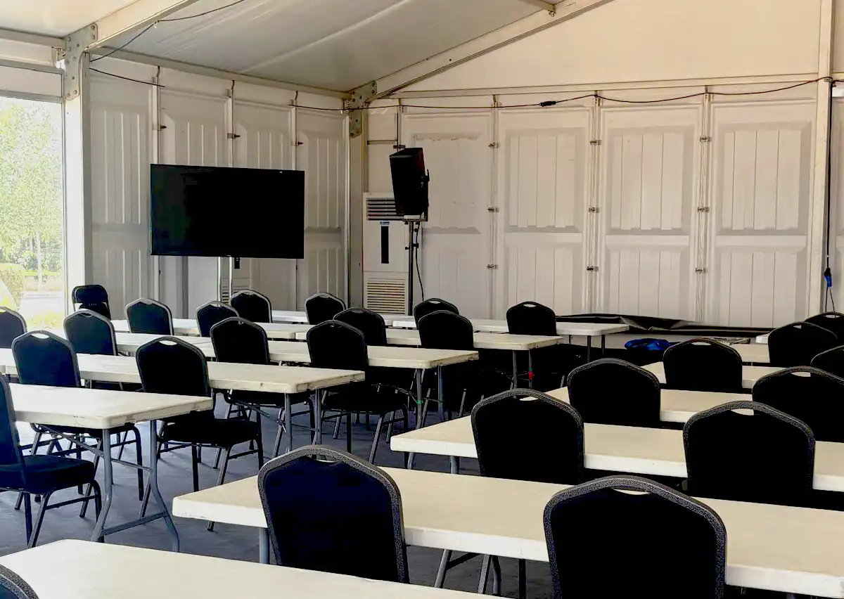 temporary cooling for golf event media centre Air conditioning unit installed inside a temporary marquee with seating and broadcast screen at a televised golf event.