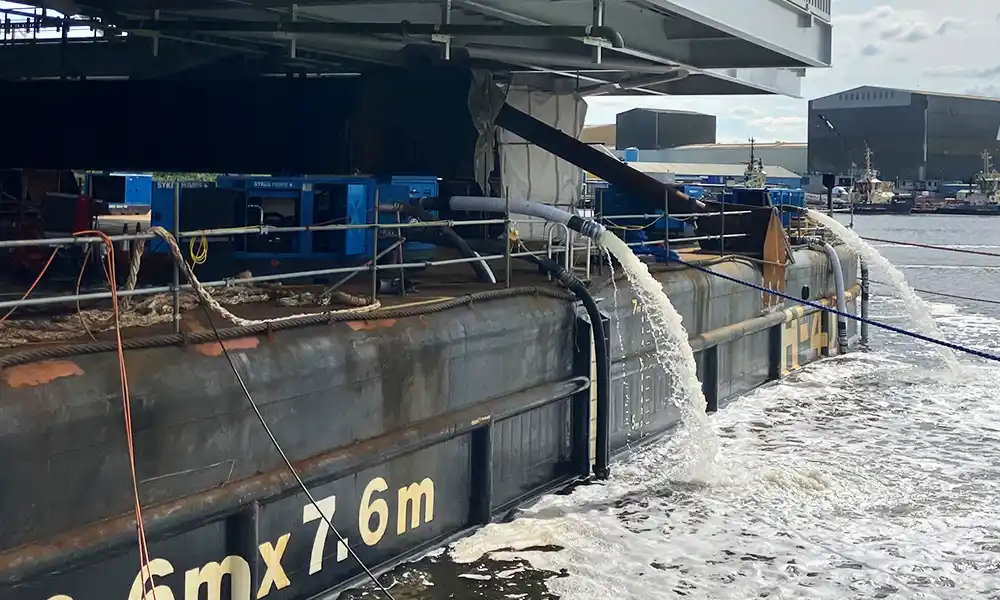 Engineer monitors manifold and hoses as submersible pumps balance barge trim for heavy module transfer Sykes Pumps ballast control keeps schedule on heavy-lift barge
